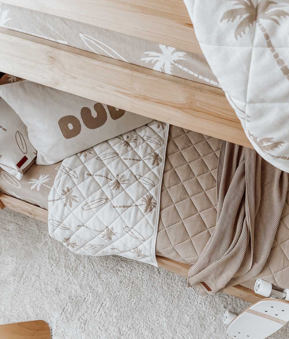 Bunk bed with a Surfing Palm reversible quilt over the top rail and its sand quilted reverse on the lower bunk