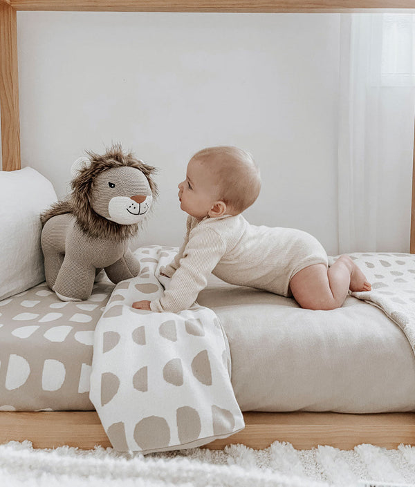 A baby is playing with a DUVET COVER - MOON PHASE from Bengali Collections on a bed.