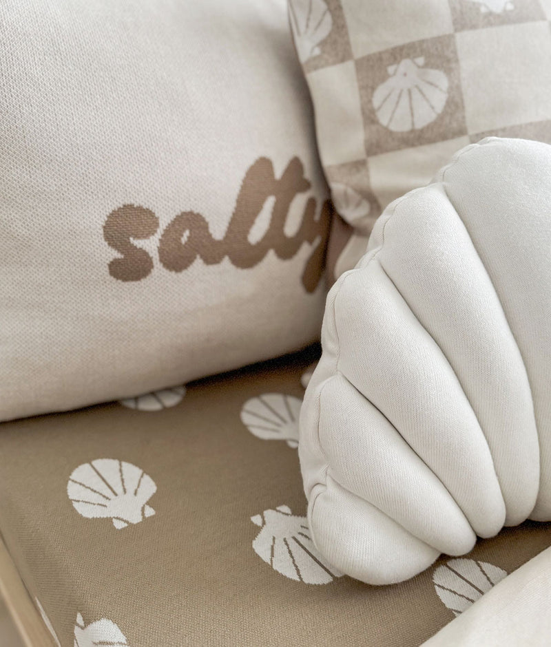 Close-up of the Salty Days pillowcase's stone lettering beside a shell cushion on a shell print sheet