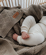 Close-up of the stone shell stitch texture with a baby in cream knitwear resting on it