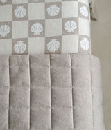 Close-up of the dune quilted stitching beside shell check bedding