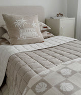 Dune quilt across a bed with a campervan palm cushion and shell check bedding