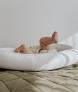 Baby settled in the olive and ivory lounger nest on an olive quilt