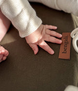 Baby hand on the olive lounger base beside the leather Bengali tab