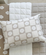 Shell check pillow resting on an ivory quilt with the dune quilt layered underneath