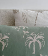 Close-up of a dune palm print pillow above a sage green palm blanket