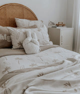 Kids bed with a rattan headboard, dune palm bedding, a check cushion and a bunny soft toy