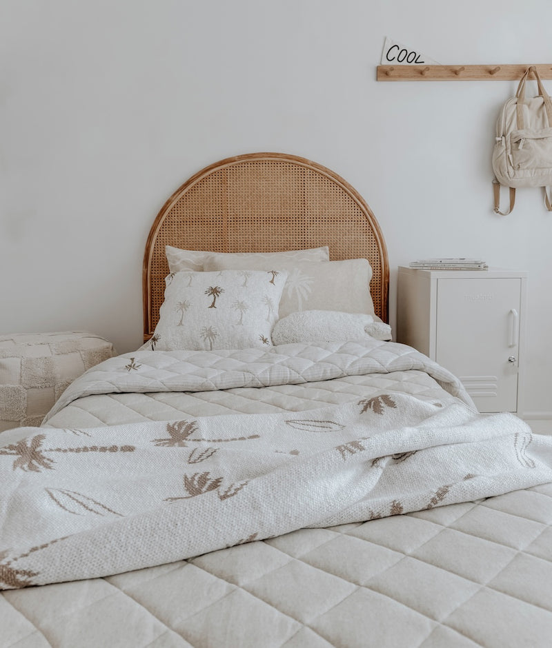 Rattan bedhead kids bed styled with the Palma palm cushion cover and a palm print quilt