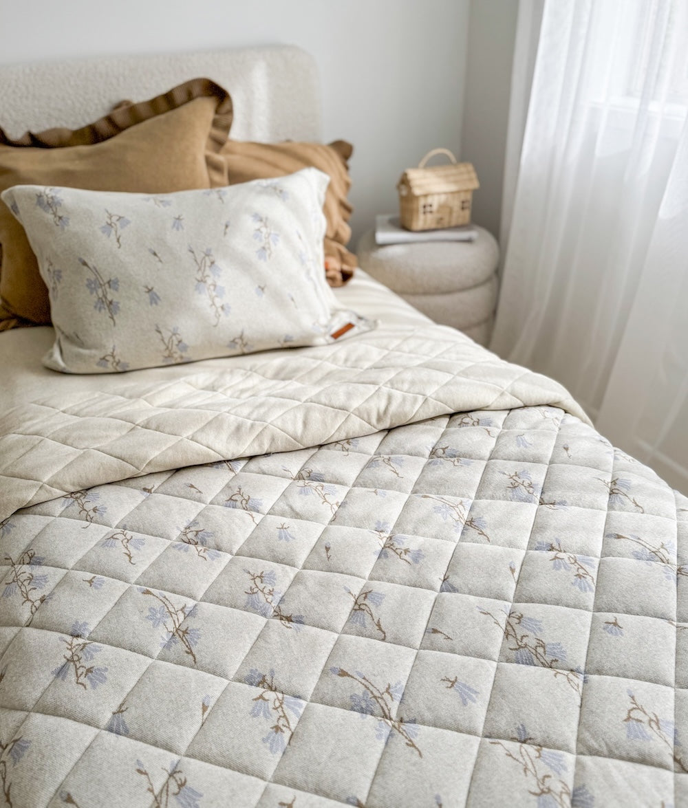 Single bed with a floral quilt and the khaki frill euro pillowcase layered at the back
