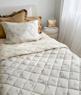 Single bed with a floral quilt and the khaki frill euro pillowcase layered at the back