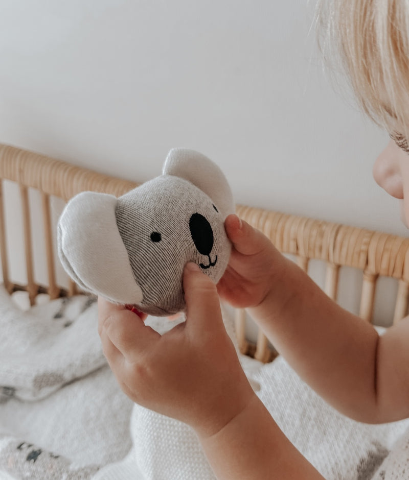 Child holding the Koala baby comforter snuggly, a grey koala head on an ivory cuddle cloth