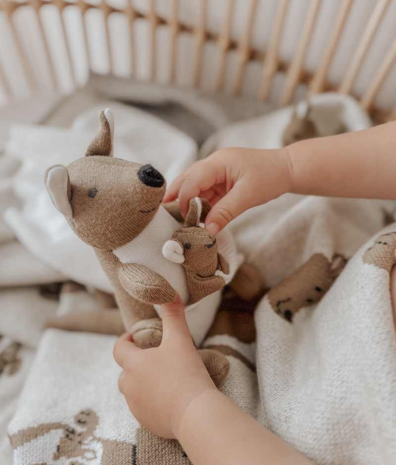 Child's hands playing with the joey on the Kangaroo comforter snuggly over a kangaroo knit blanket
