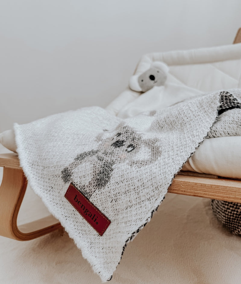 Koala baby comforter on a baby bouncer with a koala knit blanket draped over the side