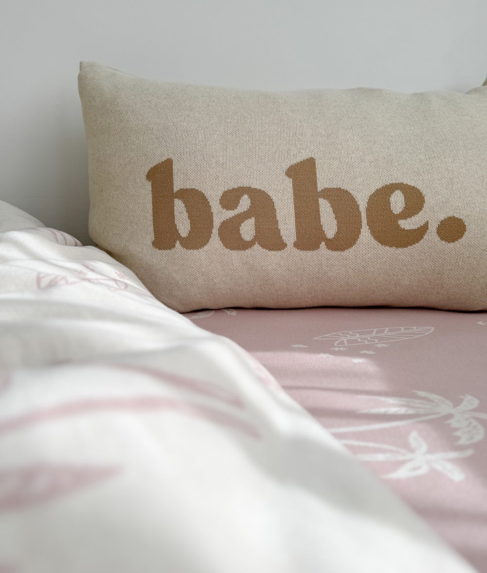 Babe pillowcase with a white throw folded across a pink fitted sheet