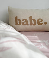 Babe pillowcase with a white throw folded across a pink fitted sheet