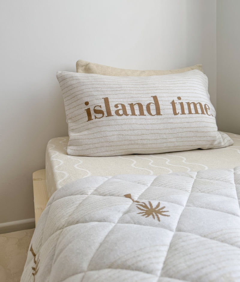 Island Time cotton pillowcase with khaki lettering on ivory marle, on a quilted kids bed