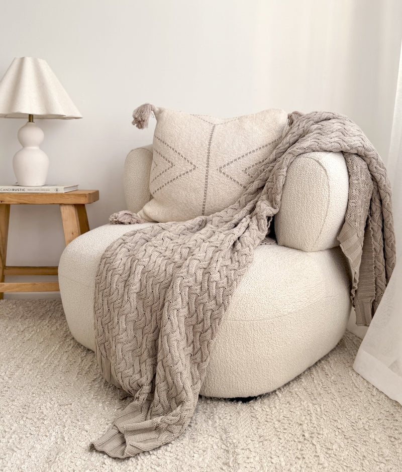 Greige Wave Lounge Throw spilling over a round boucle armchair in a light neutral room