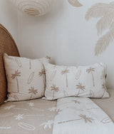 Corner of a bed with dune palm pillows layered on the matching dune fitted sheet