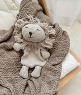 Greige knitted lion comforter lying on the stone shell stitch blanket