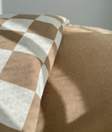 Close-up of a gingham check pillowcase resting against the plain khaki duvet cover