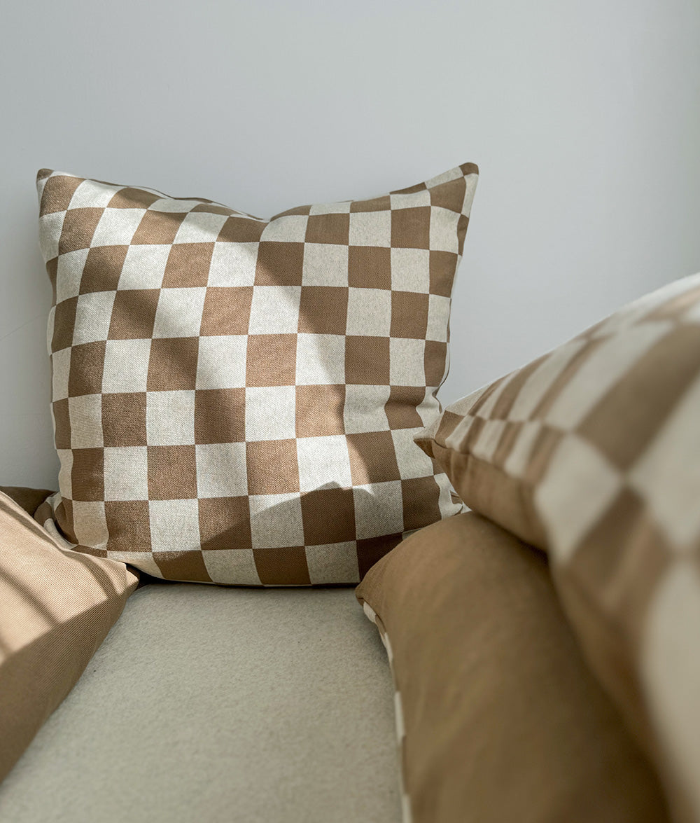 Square khaki gingham check euro pillowcase standing against a wall above khaki bedding