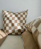 Square khaki gingham check euro pillowcase standing against a wall above khaki bedding