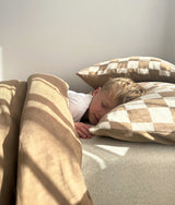 Child sleeping on the khaki gingham pillowcase in morning light