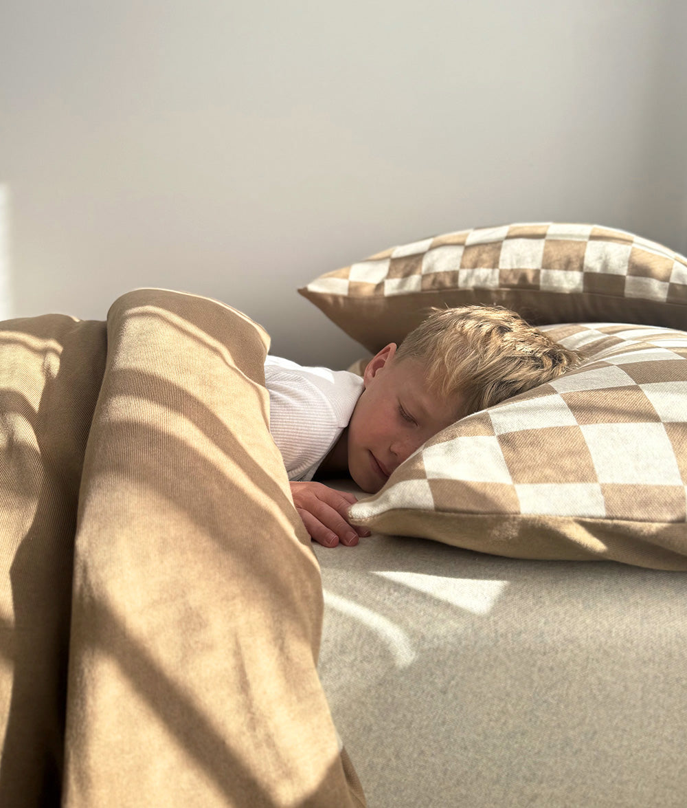 Child asleep on khaki gingham bedding with the khaki duvet pulled across