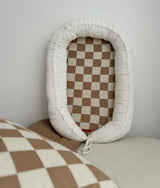 Khaki gingham baby lounger nest standing beside matching check bedding