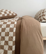Two beds dressed with khaki gingham bedding and the plain khaki duvet reverse showing