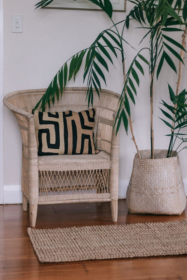 A Garcia Home Jute Rug Bubble Natural Brown next to a natural potted plant.