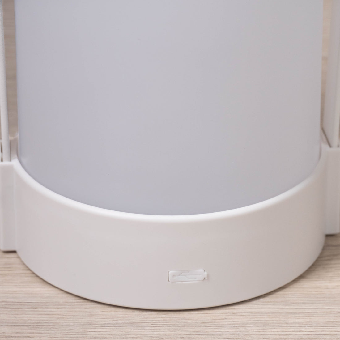Close up of the base of the white portable LED lamp showing the moulded rim and small brand mark