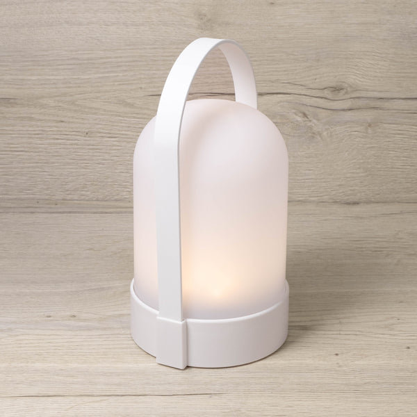 White portable LED lamp with its arched handle, lit and standing on a timber surface