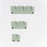 A set of four Alfa Wall Hooks, in green plastic material, on a white surface, perfect for organization and branded by Garcia Home.