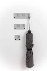 A grey umbrella hanging on an Alfa Wall Hooks Set - Various Colours by Garcia Home.