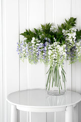 Artificial White Wisteria Spray flowers in a vase on a table with floral styling, by Artificial Flora.