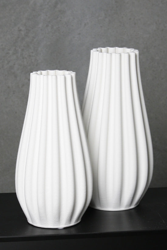 The small and large white Steffi vases side by side against a dark wall