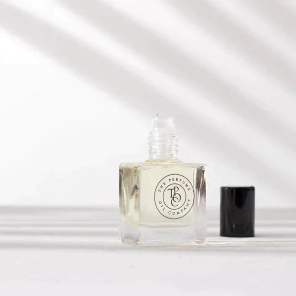 Roll-on perfume oil bottle and cap with leaf shadows on the wall behind