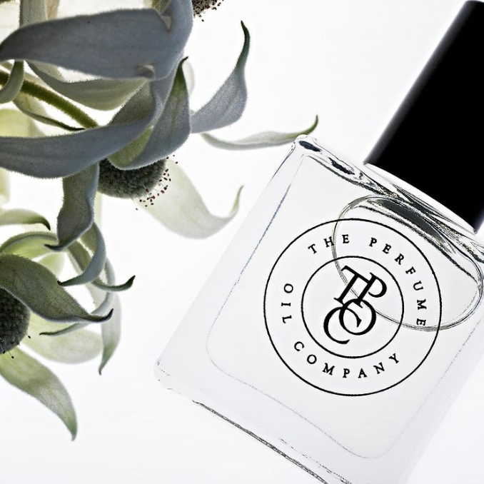 A designer fragrance gift, GYPSY - inspired by Gypsy Water (Byredo) perfume, resting alongside a flower.