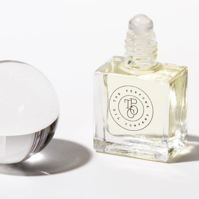 A bottle of GHOST fragrance by The Perfume Oil Company next to a glass ball.