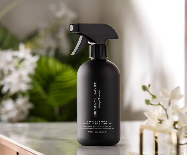 Black Therapy Kitchen surface spray on a marble bench with white blossoms behind