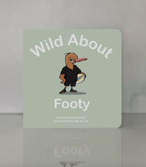 Wild About Footy standing on a glossy surface, cover reflected below