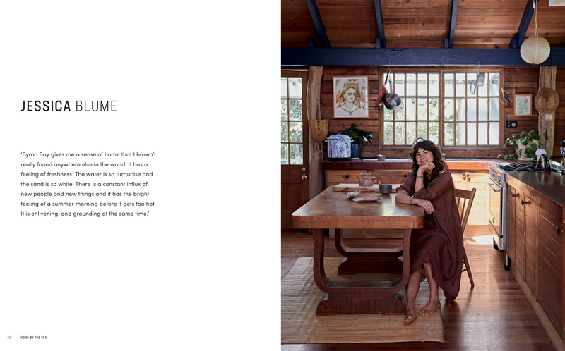 A woman sits at a table in her kitchen while reading the Home By The Sea interiors book by Books.