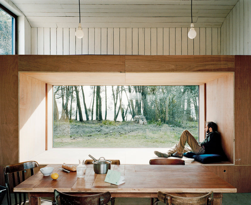 A person sitting at a table in front of a window, immersed in "Rock the Shack" books.