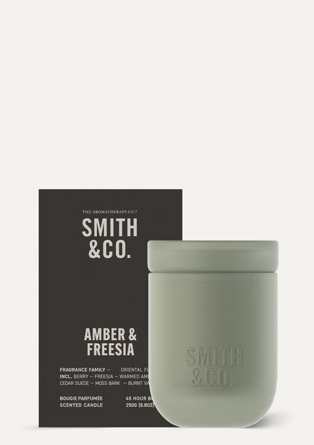 Smith and Co Amber and Freesia candle beside its black gift box