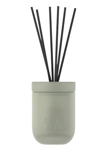 Smith and Co sage green ceramic diffuser with black reeds on a plain white background