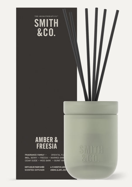 Smith and Co Amber and Freesia diffuser standing in front of its black gift box