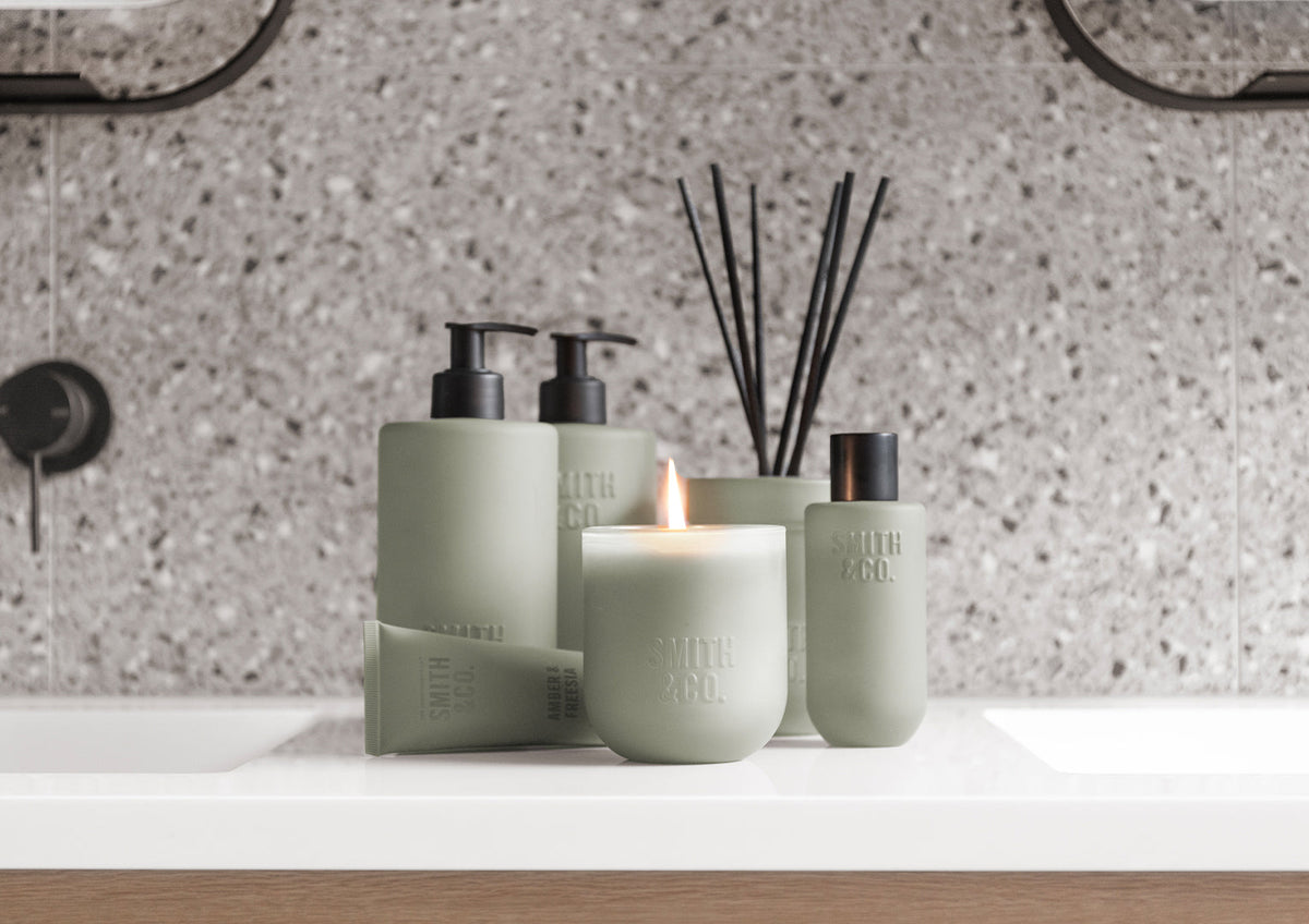 Sage green Smith and Co hand wash, lotion, candle and reed diffuser on a vanity against terrazzo