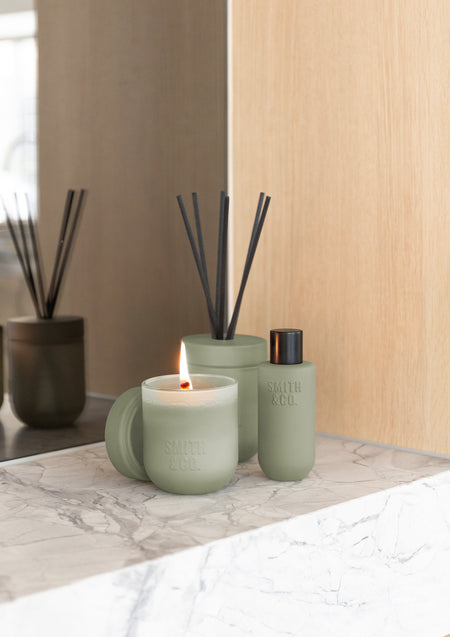 Sage green Smith & Co. candle, reed diffuser and room spray on a marble ledge against oak panels