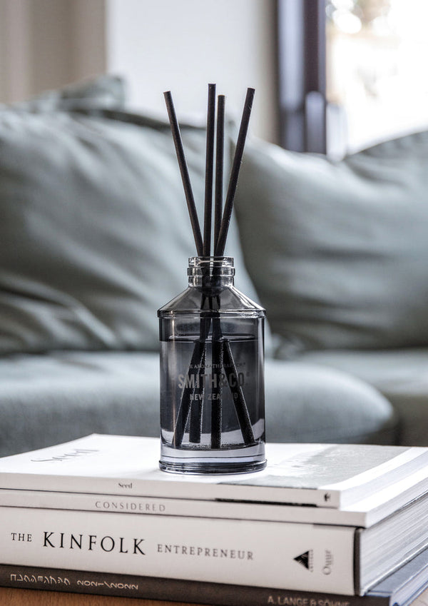 A Smith & Co diffuser - Lime & Coconut, from The Aromatherapy Co, emitting a refreshing citrus aroma, placed elegantly on top of a coffee table.